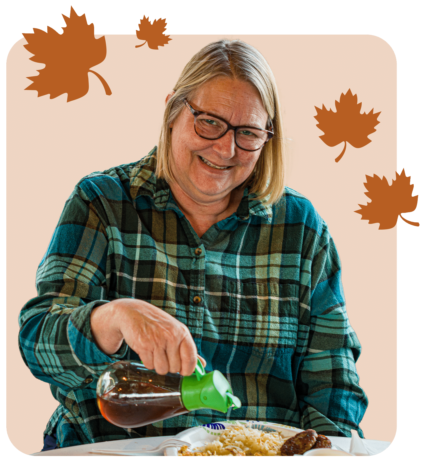 A woman wearing glasses pours maple syrup onto a plate
